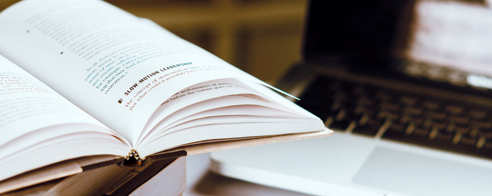 Livre ouvert devant écran d'ordinateur