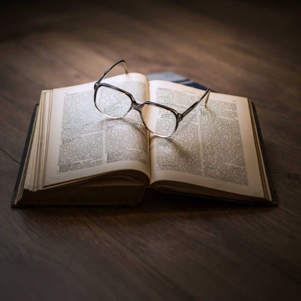 vieux livre ouvert avec lunettes posées dessus