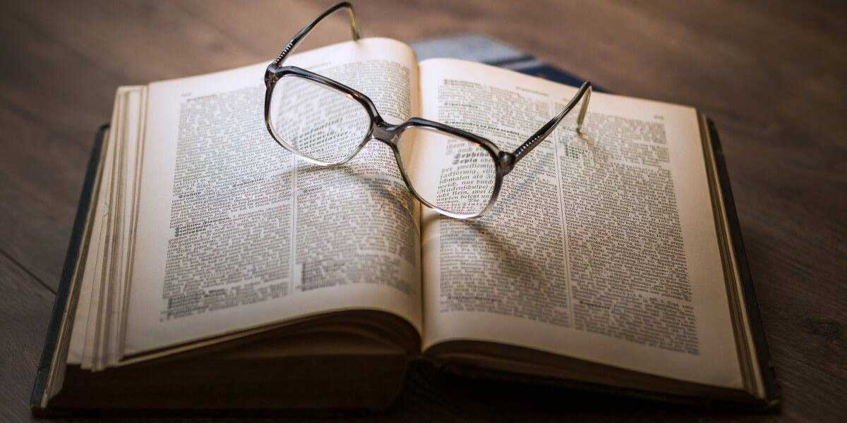 vieux livre ouvert avec lunettes posées dessus
